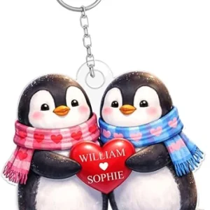 Two high-quality personalised penguin keyrings side-by-side, featuring custom engraved names on a polished metal surface.